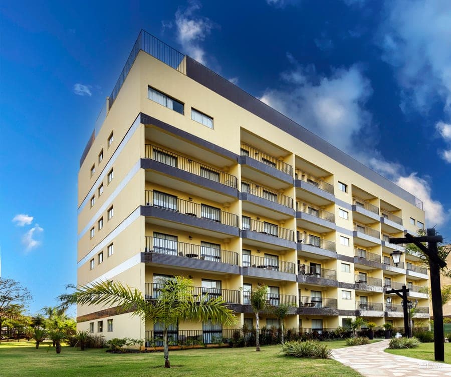 Torre de apartamentos do Barretos Country com gramado e céu azul