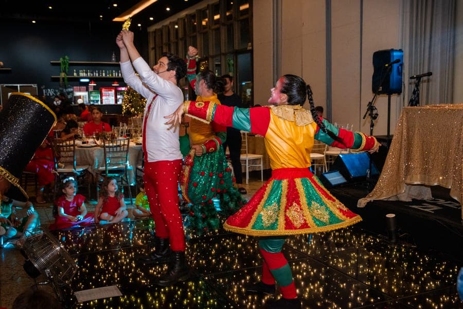 Bailarinos com figurino natalino se apresentando no salão